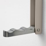 A close-up of a modern, metallic wave-shaped hook mounted on a wall, showing its high-quality design and robust hardware.