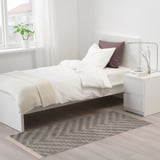KNAPPHIRS grey zigzag rug in bedroom under bed, next to nightstand, with fringe.