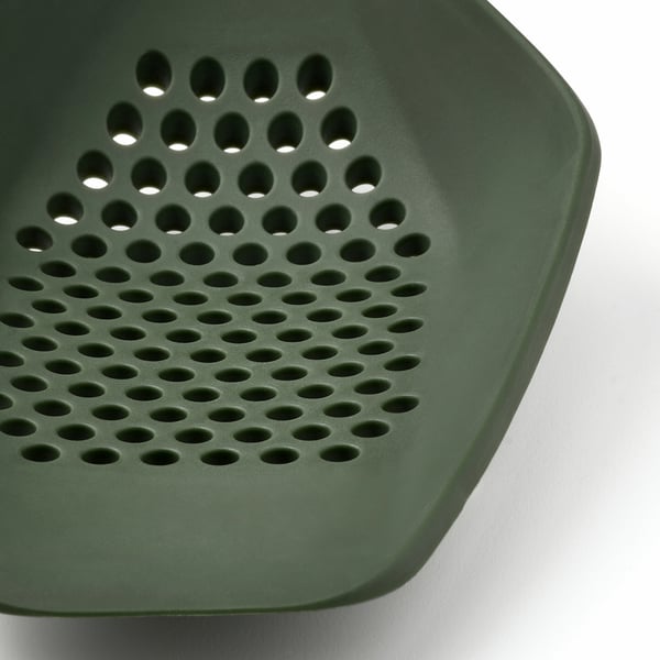 Close-up of dark green, textured kitchen utensil with numerous small holes, designed for cooking tasks. Quality materials, ergonomic design.