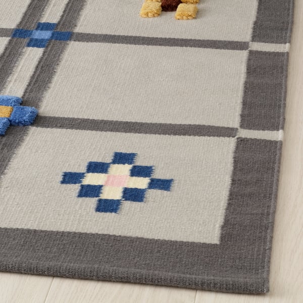 Handwoven rug featuring geometric patterns and varied textures. Neutral colors with blue accents. Wool material, durable and soft.
