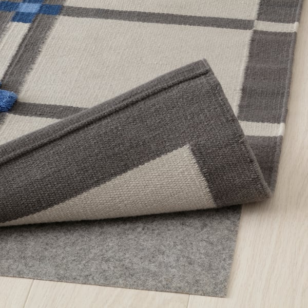 Greige and grey checkered wool rug, folded to show pile variation and warm texture, ideal for various floors.