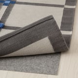Greige and grey checkered wool rug, folded to show pile variation and warm texture, ideal for various floors.