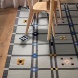 Light wooden chairs on a gray checkered wool rug with raised textures and small patterns scattered across it.