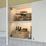 Open kitchen cabinet with top light, showing organized pantry items. Light activates when opened.