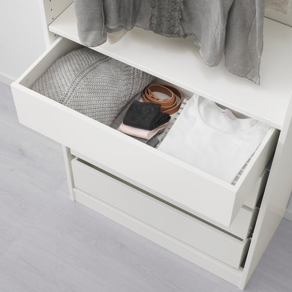 White wardrobe drawer, open showcasing folded clothes and accessories neatly organized in compartments.