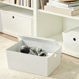 White box with cables and gadgets on carpet, bookshelf in background.