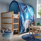 Blue starry KURA bed tent in kids room, covering bunk bed, creating cozy play space.