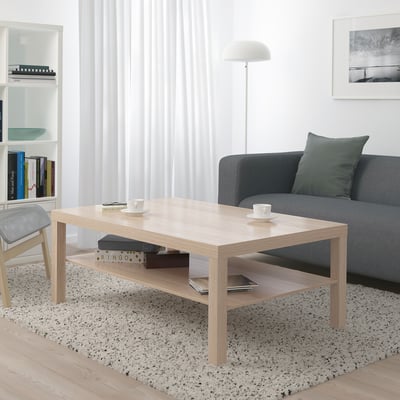 Modern living room with LACK coffee table, grey sofa, rug, bookshelf, and floor lamp.