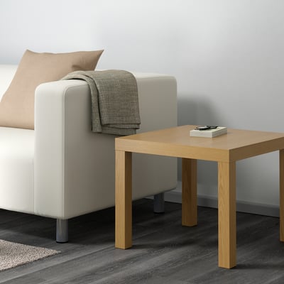 Oak LACK side table next to cream couch with book.