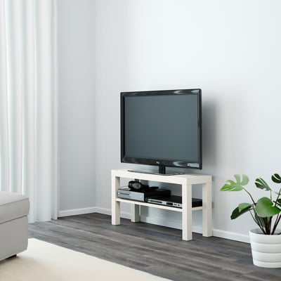 Small white LACK tv stand holds a flat screen, electronics, and plant. Sits low, fits neatly in corner of minimalist room.