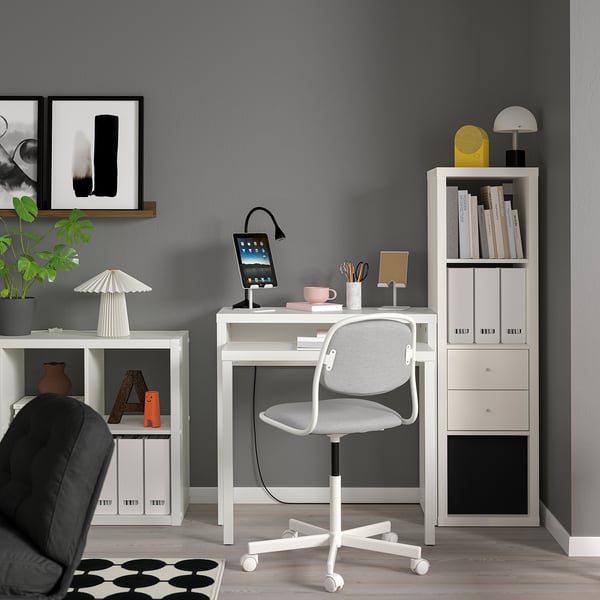 Modern minimalist home office: white LÄNGDHOPP desk with grey chair. Grey wall, bookshelf, and art. Bright, clean, and organised.
