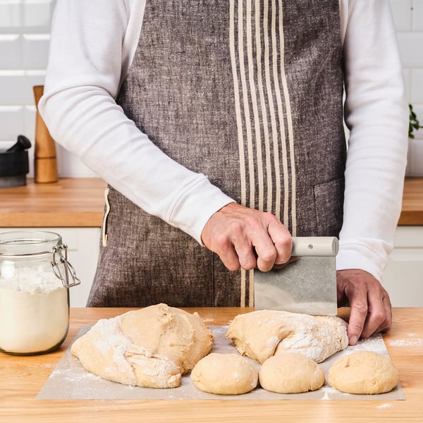 Person dividing dough with a cutter on a floured board.