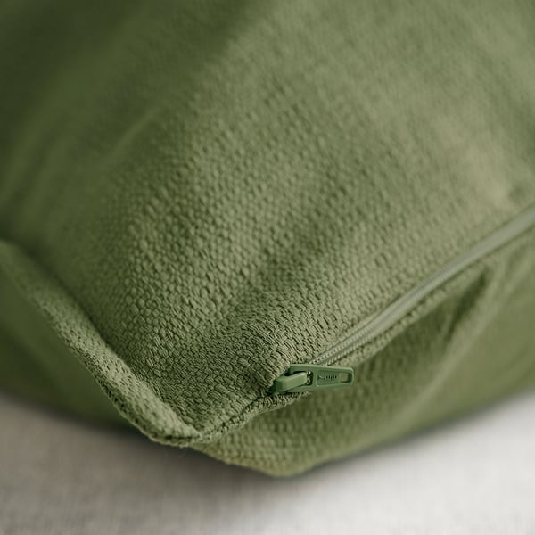 Close-up of green cushion cover with zipper, showcasing its textured, matte finish. Quality detail of the stitching visible.