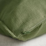 Close-up of green cushion cover with zipper, showcasing its textured, matte finish. Quality detail of the stitching visible.