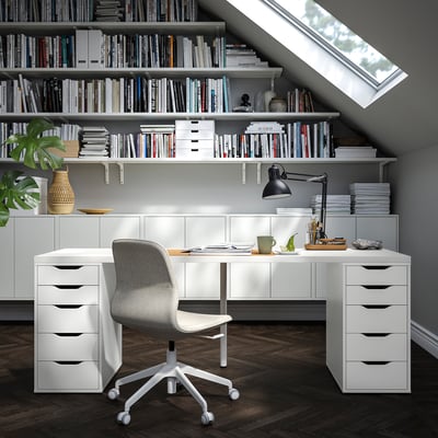 Home office with white LAGKAPTEN desk, grey chair, lamp, and books under skylight.