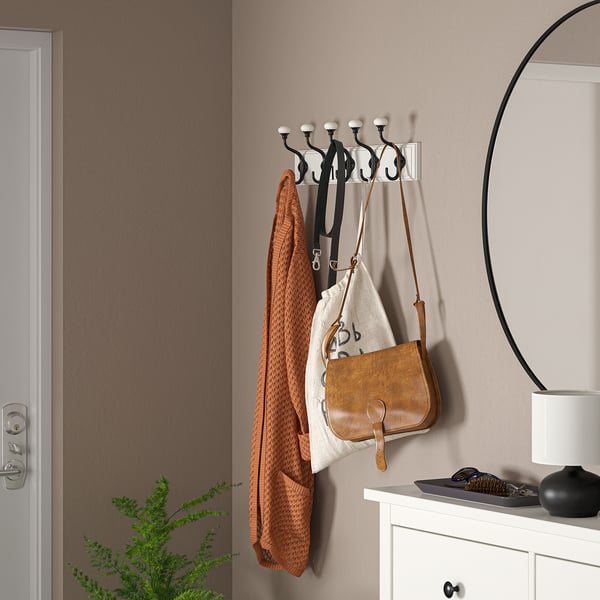 Black LANDKRABBA rack with 5 hooks, holding orange sweater, bag, and straps. Beside dresser and mirror.