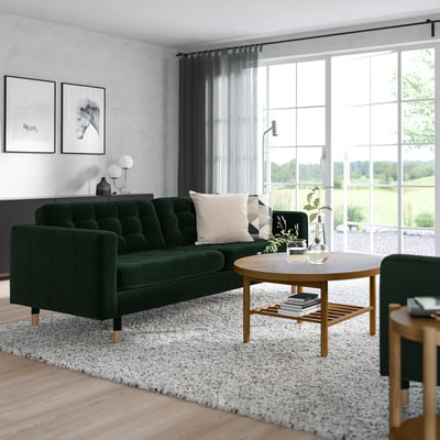 Modern living room featuring dark green LANDSKRONA sofa, wooden coffee table, rug, and large window. Minimalist decor with natural light.