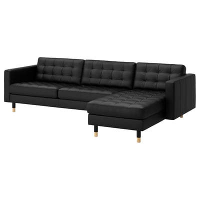 Black leather l-shaped sofa with tufted cushions and wooden legs.