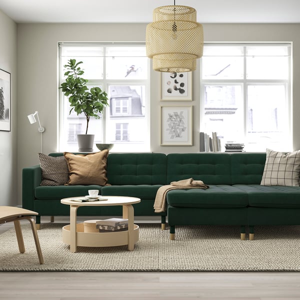 Modern living room: dark green låndeskrona sofa, large, with wooden coffee table, cushions, plant, and pendant lamp.