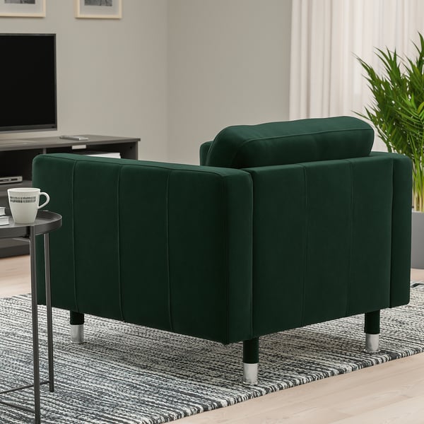 Dark green armchair with metal legs in cozy room, beside small table with a mug.