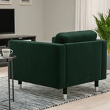 Dark green armchair with metal legs in cozy room, beside small table with a mug.