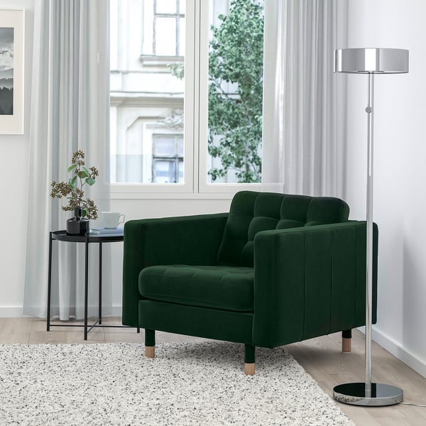 Dark green velvet LANDSKRONA armchair with wooden legs, modern lamp, and speckled rug near a window.