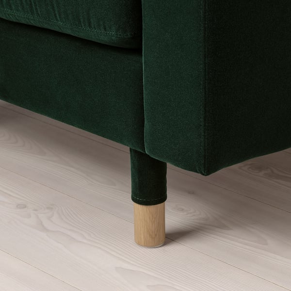 Dark green upholstered furniture with wooden legs on a light wooden floor.