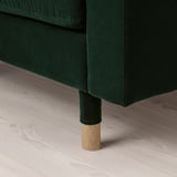 Dark green upholstered furniture with wooden legs on a light wooden floor.