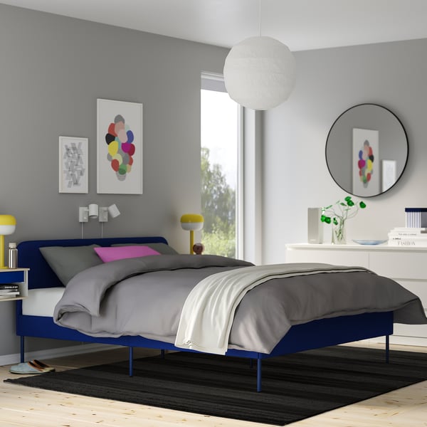 Modern bedroom with dark rug, queen bed, art, and mirrors.