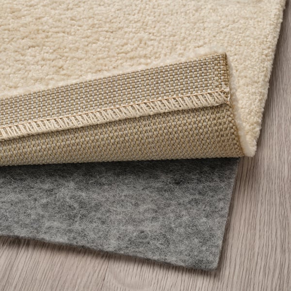 Layers of rug with carpet backing and anti-slip mat.