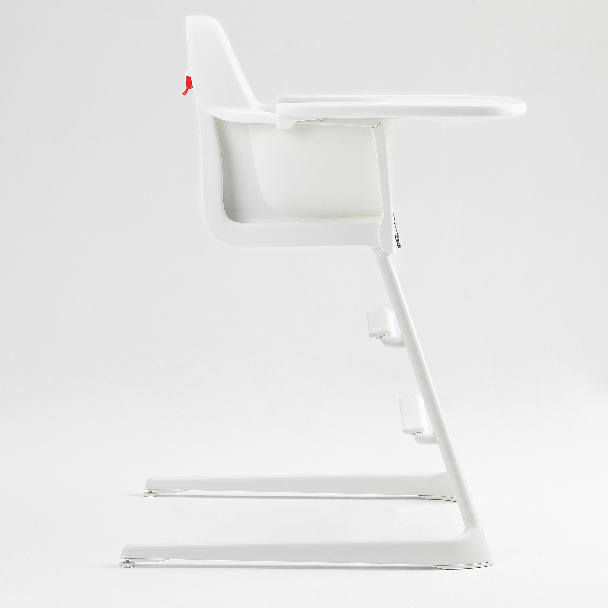 White highchair, side view. Stable, clean design. Adjustable feet, safety belt, tray.