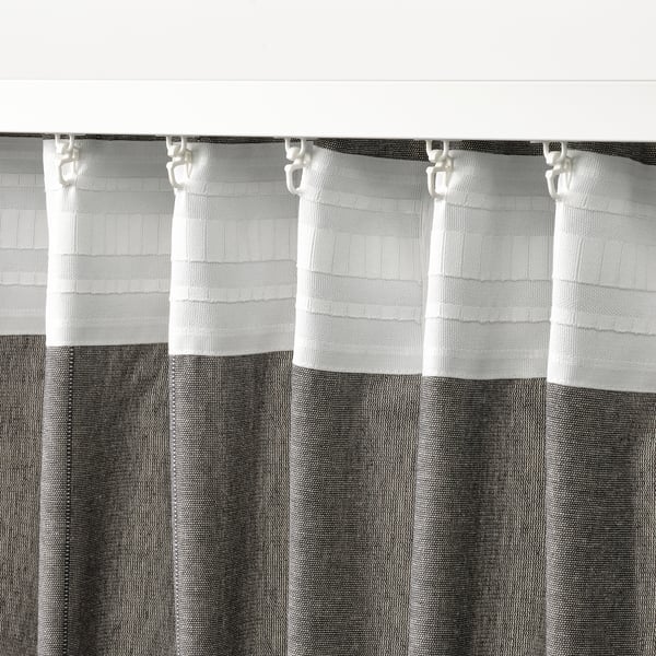 Grey curtains with header tape hang from hooks, adding texture and privacy while letting in light.