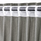 A pair of LENDA curtains in dark grey hanging, featuring header tape and linear weave, offering privacy and daylight.