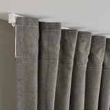 Grey curtains with header tape, pleated by hooks, ensure privacy and light.
