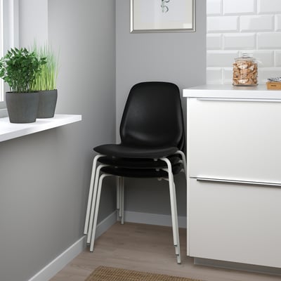 Black LIDÅS chair, sleek modern design, reinforced plastic seat, white metal legs, stackable.