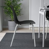 Black chair with white legs, designed for comfort and flexibility. Stackable, easy to clean. Ideal for indoor dining.