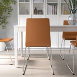 Modern dining chair with brown padded seat and chrome base, designed for comfort and durability.