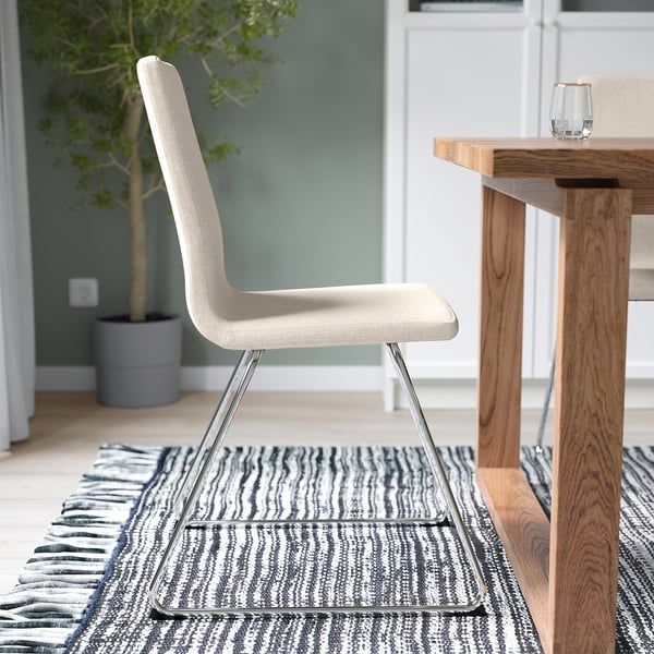 Modern beige office chair with chrome base on striped rug beside wooden table.