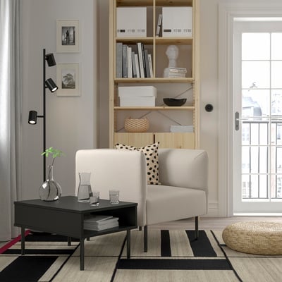 Modern living room with gray LILLEHEM sofa, black coffee table, wooden bookshelf, and beige rug. Sofa has a single seat module with abstract pillows.
