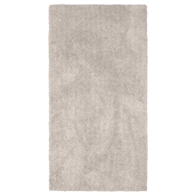 A rectangular, beige LINDKNUD rug. Made from recycled polyester, it has a soft, plush surface ideal for bedrooms.