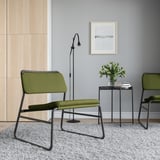 Modern minimalist corner with LINNEBÄCK green chairs, sleek black metal frames, textured gray rug, and simple decor.