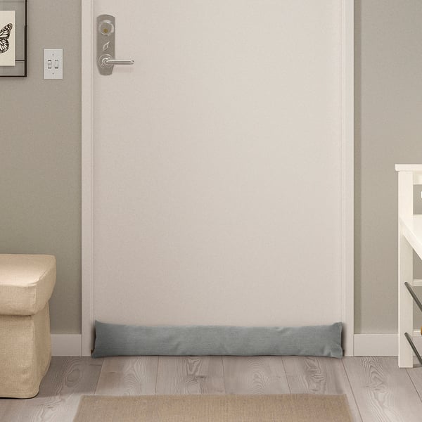 Small grey door draft stopper on floor under door, minimal design complements any space.