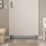 Small grey door draft stopper on floor under door, minimal design complements any space.