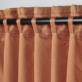 Brown curtains with looped heading tape hang from black rod, showcasing thick, jacquard-woven pattern.