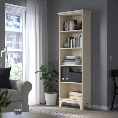 Neutral LOMMARP bookshelf against dark wall, filled with books and decor, with adjustable shelves.