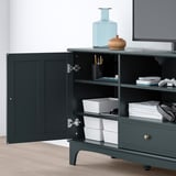 Dark green LOMMARP tv stand with open door revealing storage compartments and organization solutions, including a drawer and stacks of white boxes.