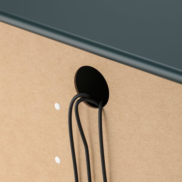 Black cable management clip attached to beige cork board, demonstrating neat cable routing.