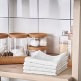 White cotton towels stacked neatly on a wooden shelf, ideal for gym or travel.