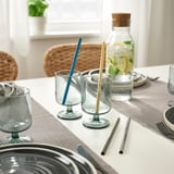 Table set with clear glasses, stainless steel straws, and a pitcher of lemon water.
