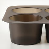 Dark silicone ice cube tray with large, circular compartments, placed on a white surface.